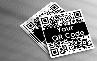 Custom vinyl QR code stickers spread out on metal table.