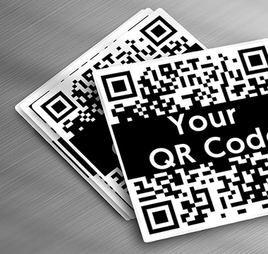 Custom vinyl QR code stickers spread out on metal table.